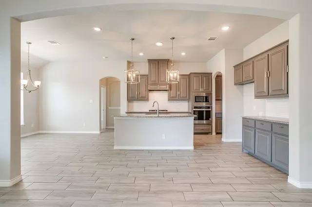a large kitchen with cabinets a sink a window and stainless steel appliances