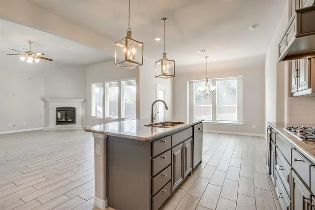 a kitchen with stainless steel appliances granite countertop a sink a stove and a wooden floors