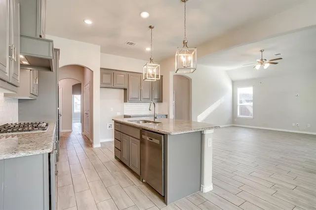 a kitchen with stainless steel appliances granite countertop a sink a stove and a wooden floors
