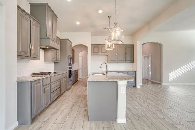 a large kitchen with granite countertop a large center island a sink stainless steel appliances and cabinets