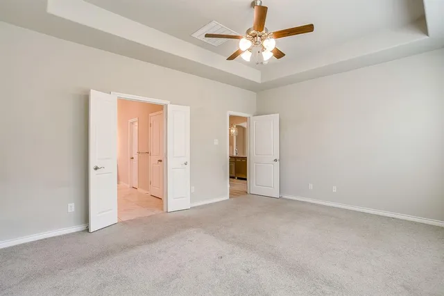 an empty room with chandelier fan and windows