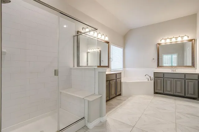 a bathroom with a tub a double vanity sink and mirror
