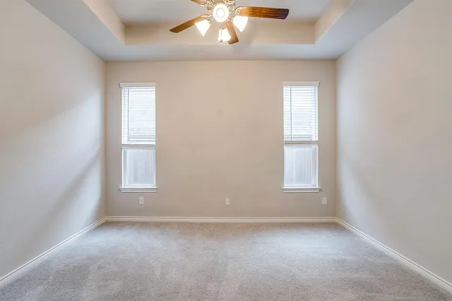 an empty room with windows and chandelier fan