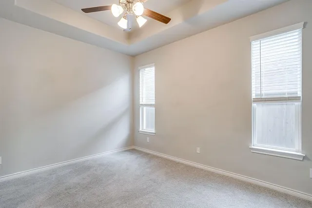 an empty room with windows and chandelier fan