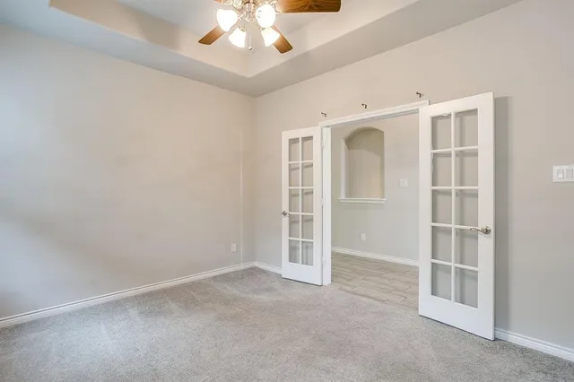 an empty room with a windows and chandelier fan