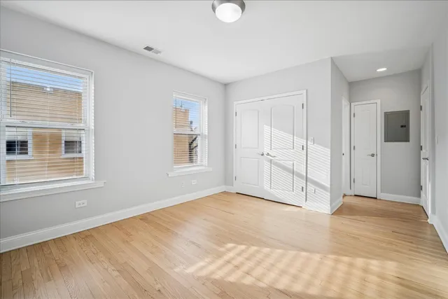 a view of an empty room with window and wooden floor