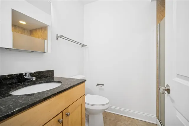 a bathroom with a granite countertop sink toilet and mirror