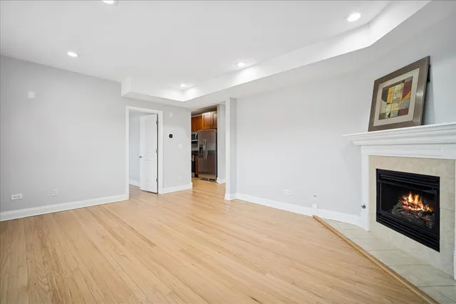 a view of an empty room with wooden floor fireplace and a window