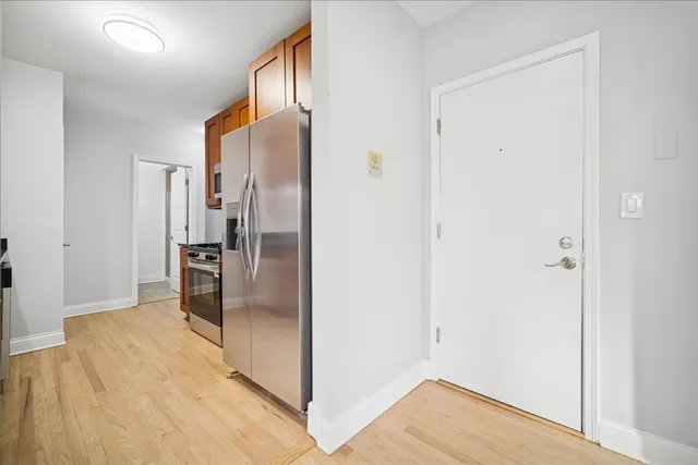 a view of a kitchen with a refrigerator and wooden floor