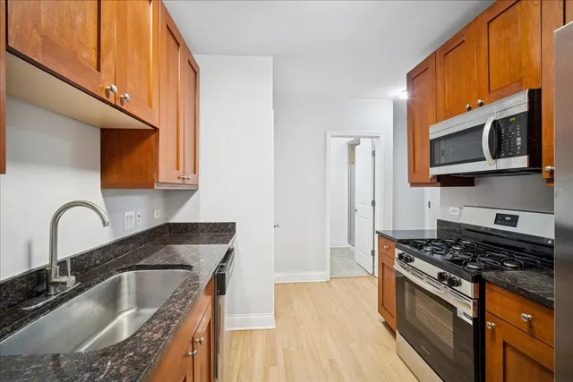 a kitchen with granite countertop a sink stainless steel appliances and cabinets