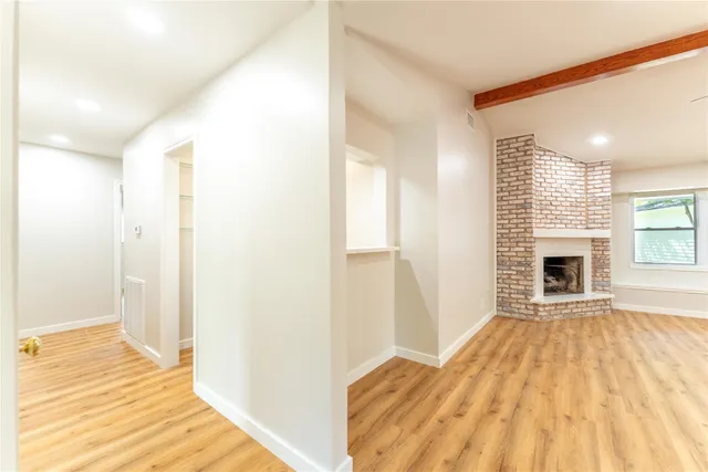 a view of empty room with wooden floor and fireplace