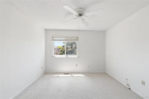 an empty room with a window and a ceiling fan