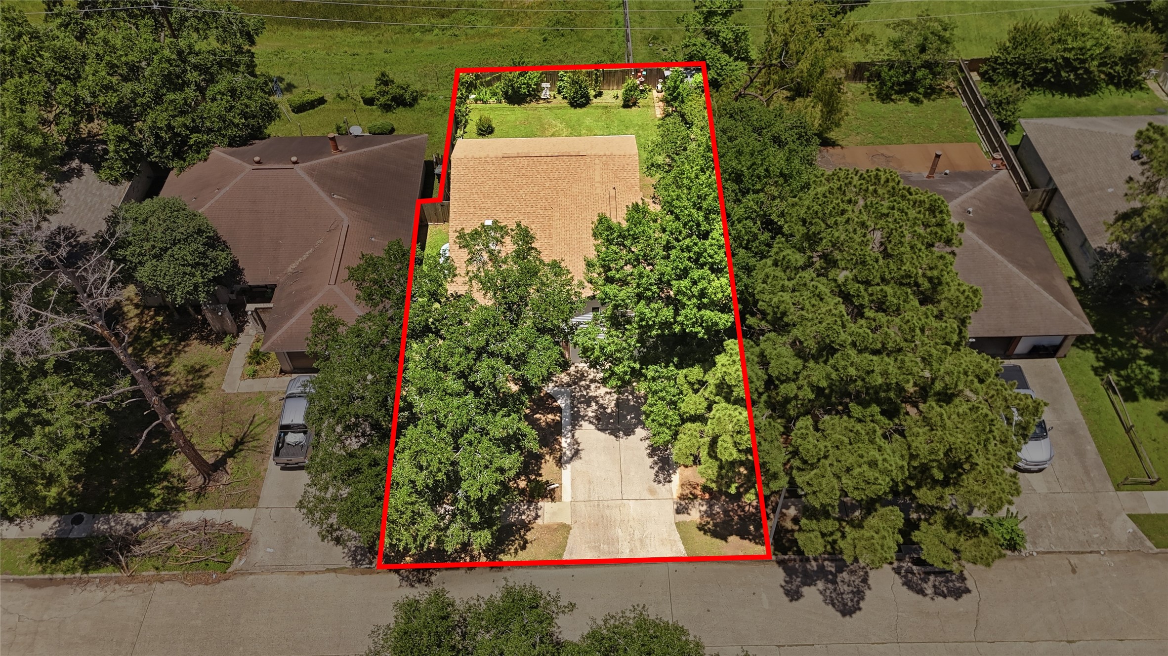 4718 Temple Bell Drive Spring, TX 77388 - Photo 42 of 50 This aerial view shows a single-story house with a tan roof, surrounded by trees for privacy. The property is outlined in red, featuring a spacious yard and a driveway leading to the street.