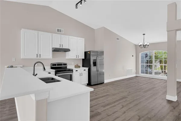 a kitchen with stainless steel appliances a sink a stove a refrigerator cabinets and a dining table