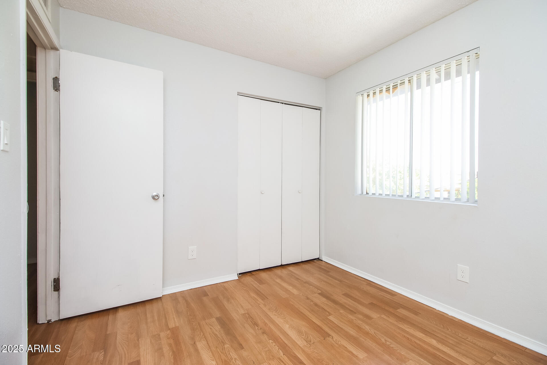 1050 West University Drive, Unit 201 Mesa, AZ 85201 - Photo 12 of 15 a view of an empty room with wooden floor and a window