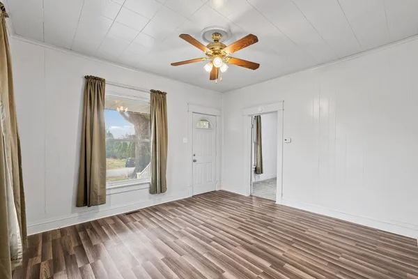 a view of an empty room with wooden floor and a window