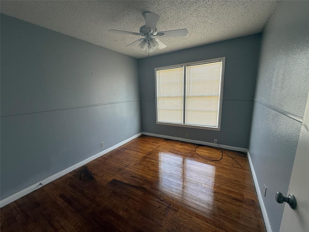 501 Needham Street Coleman, TX 76834 - Photo 12 of 16 an empty room with wooden floor and windows