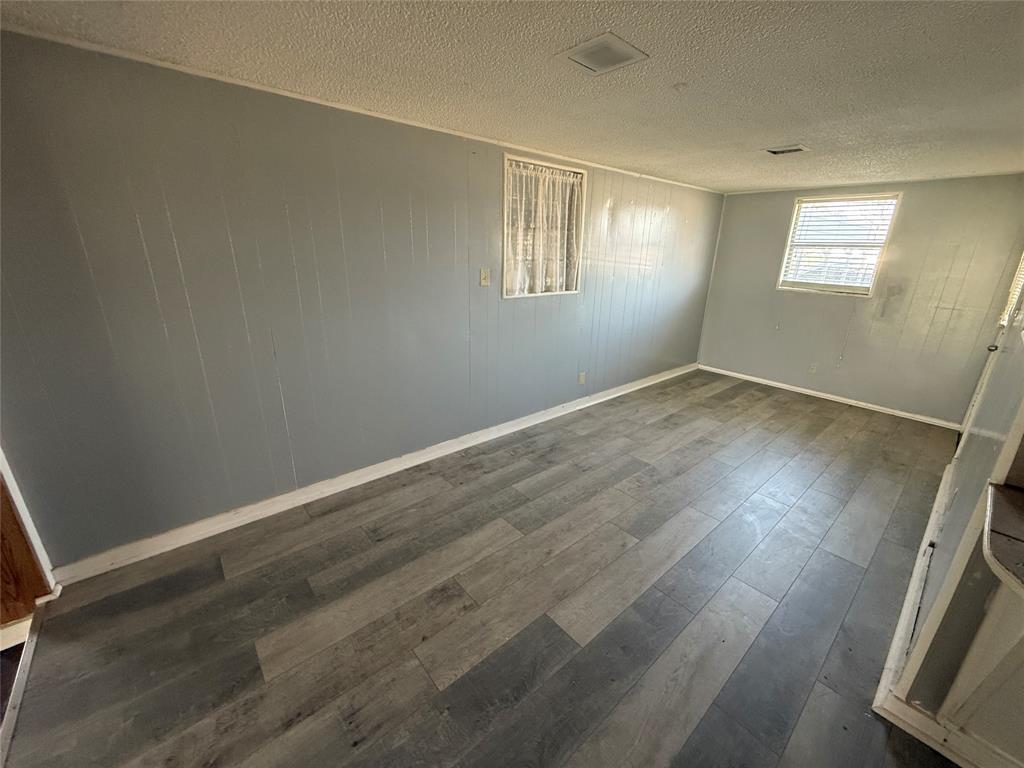 501 Needham Street Coleman, TX 76834 - Photo 5 of 16 an empty room with wooden floor and windows
