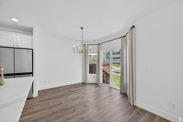 14771 Haddington Road Draper, UT 84020 - Photo 15 of 44 Bright dining area featuring wood-finish flooring, a contemporary gold chandelier, and direct access to an outdoor deck through sliding glass doors
