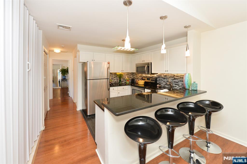 20 Parkside Court Wayne, NJ 07470 - Photo 7 of 22 a kitchen with stainless steel appliances granite countertop a sink a refrigerator and chairs