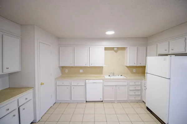 a kitchen with a sink a stove a refrigerator and white cabinets