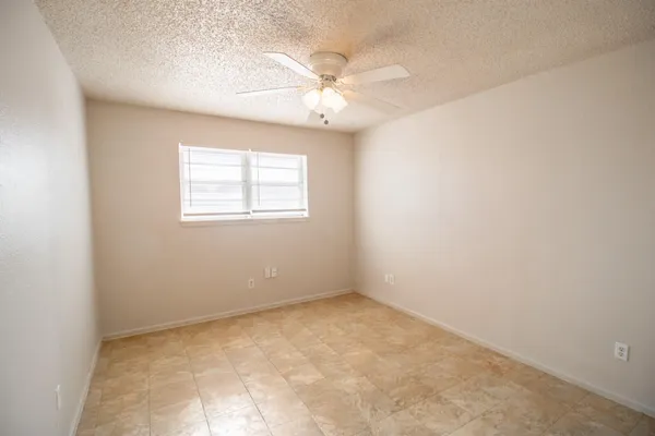 an empty room with a window and a fan
