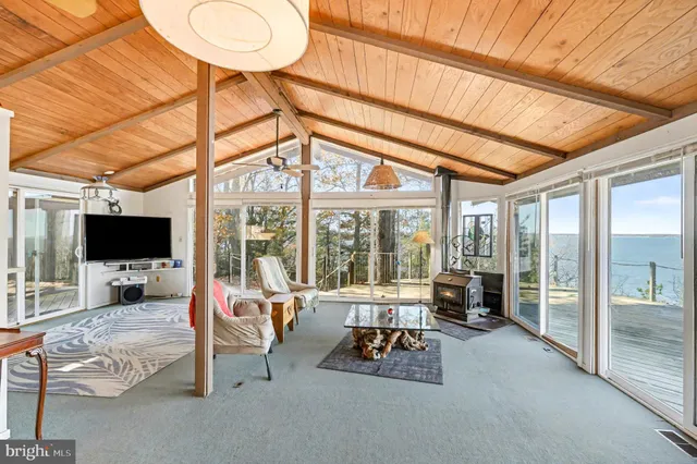 a living room with furniture a flat screen tv and a floor to ceiling window