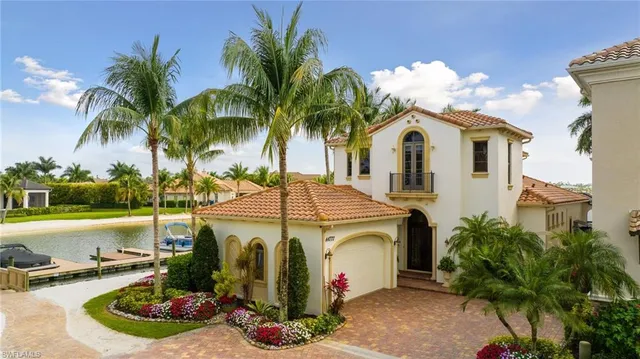 a view of a white house with a swimming pool and lawn chairs under an umbrella