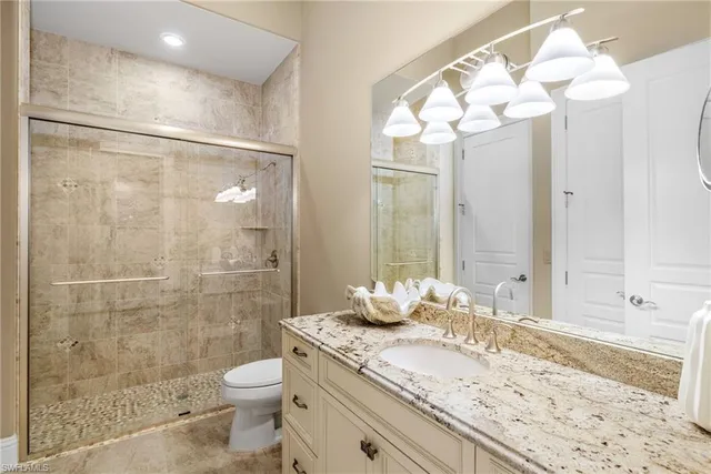 a bathroom with a granite countertop sink a toilet and shower