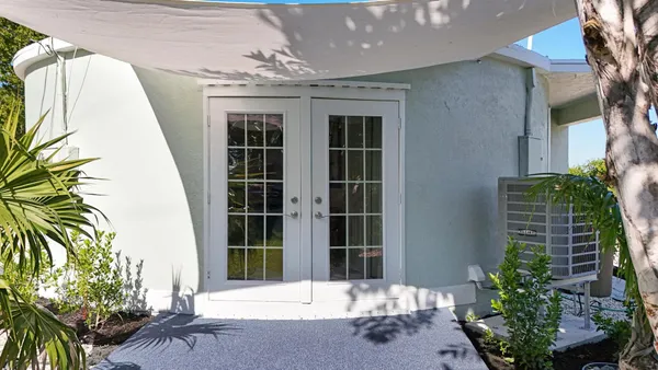 a porch with a table and chairs and potted plants
