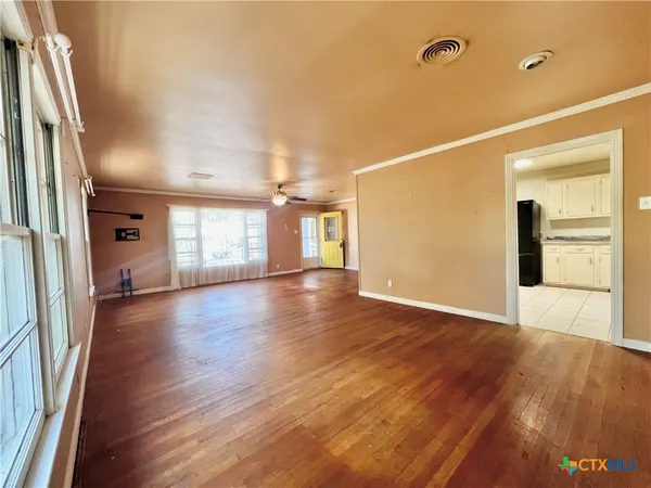 an empty room with wooden floor and windows