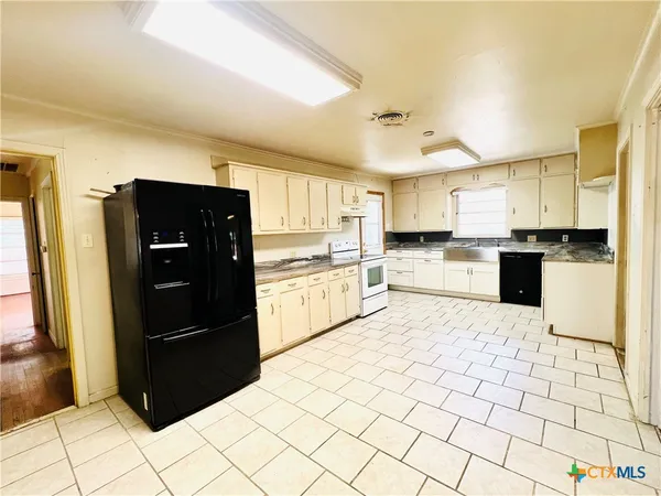 a kitchen with granite countertop a refrigerator and a stove top oven