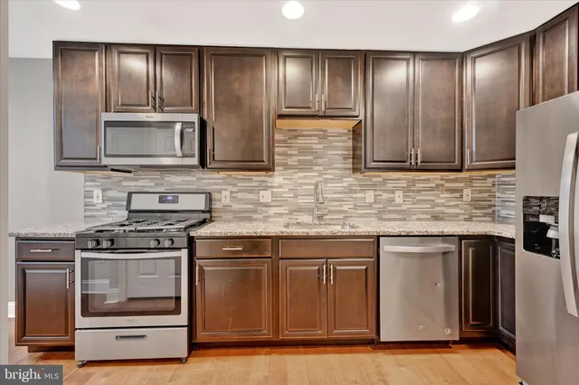 a kitchen with granite countertop wooden cabinets stainless steel appliances and a sink