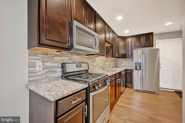 a kitchen with stainless steel appliances granite countertop a stove refrigerator sink and microwave