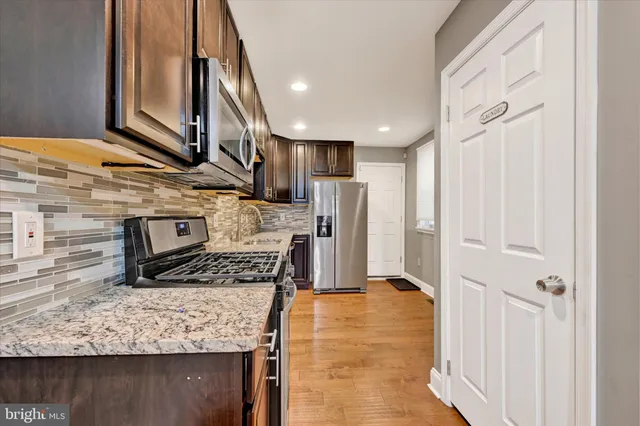a kitchen with stainless steel appliances granite countertop a sink stove and refrigerator