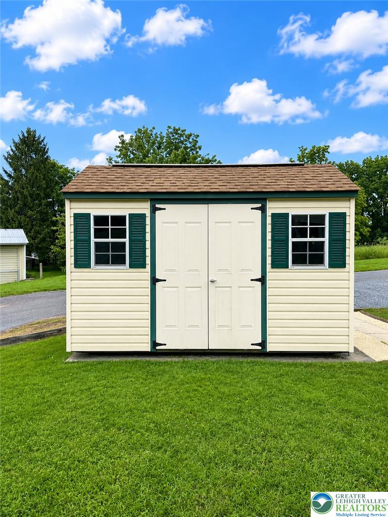 5540 Main Street Whitehall, PA 18052 - Photo 53 of 53 A quaint storage shed with classic design accents sits on a vibrant lawn.