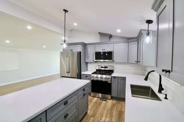 a kitchen with stainless steel appliances a stove a sink a microwave a refrigerator and cabinets