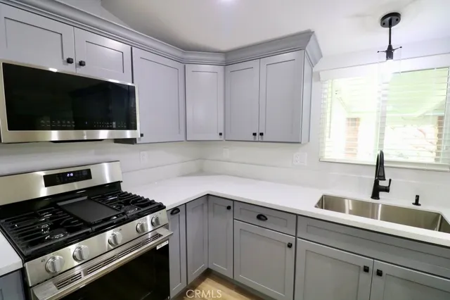 a kitchen with stainless steel appliances a sink dishwasher a stove and microwave