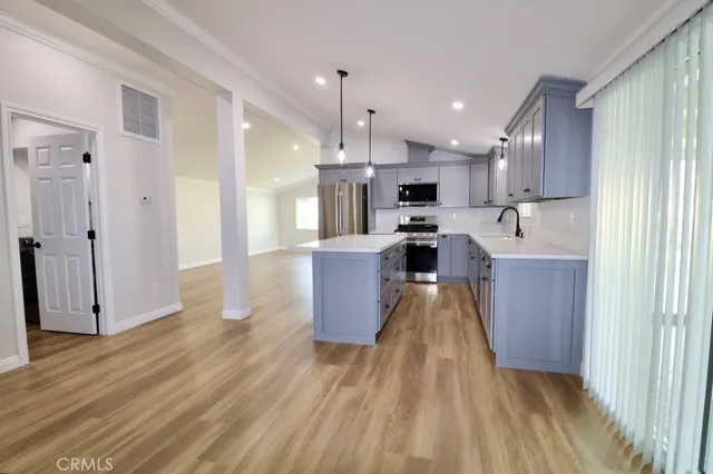 a view of a kitchen with wooden floor and electronic appliances