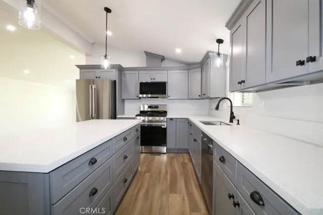 a kitchen with a sink a counter top space stainless steel appliances and cabinets