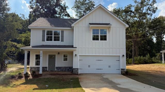 Modern inspired farmhouse featuring board and batten siding, a porch, a garage, concrete driveway, and roof with shingles