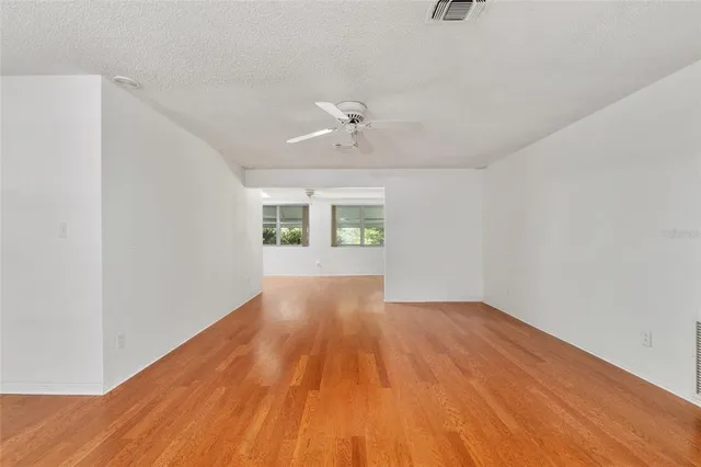 a view of an empty room with window and wooden floor