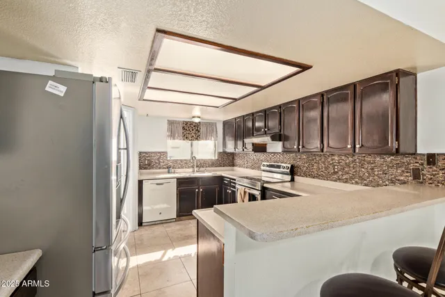 a kitchen with stainless steel appliances kitchen island granite countertop a refrigerator and a sink