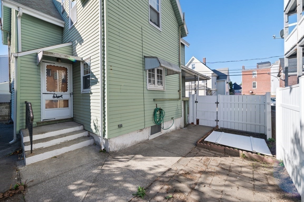 2 Perry Place Everett, MA 02149 - Photo 13 of 16 a view of a grey house with a small yard and wooden fence