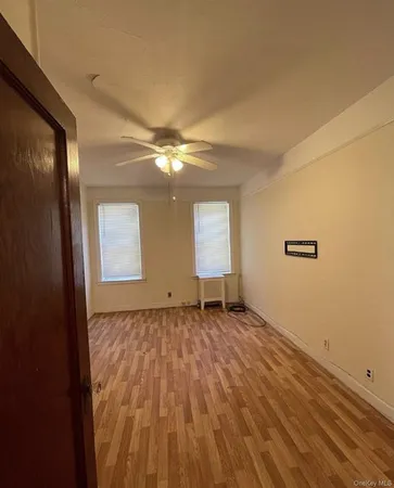 a view of an empty room with window and wooden floor