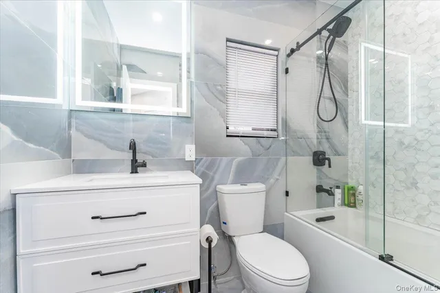a bathroom with a shower sink vanity mirror and toilet