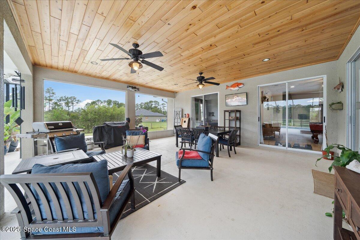 5005 Corey Road Grant Valkaria, FL 32950 - Photo 14 of 47 a view of a patio with dining table and chairs under a large umbrella with wooden floor