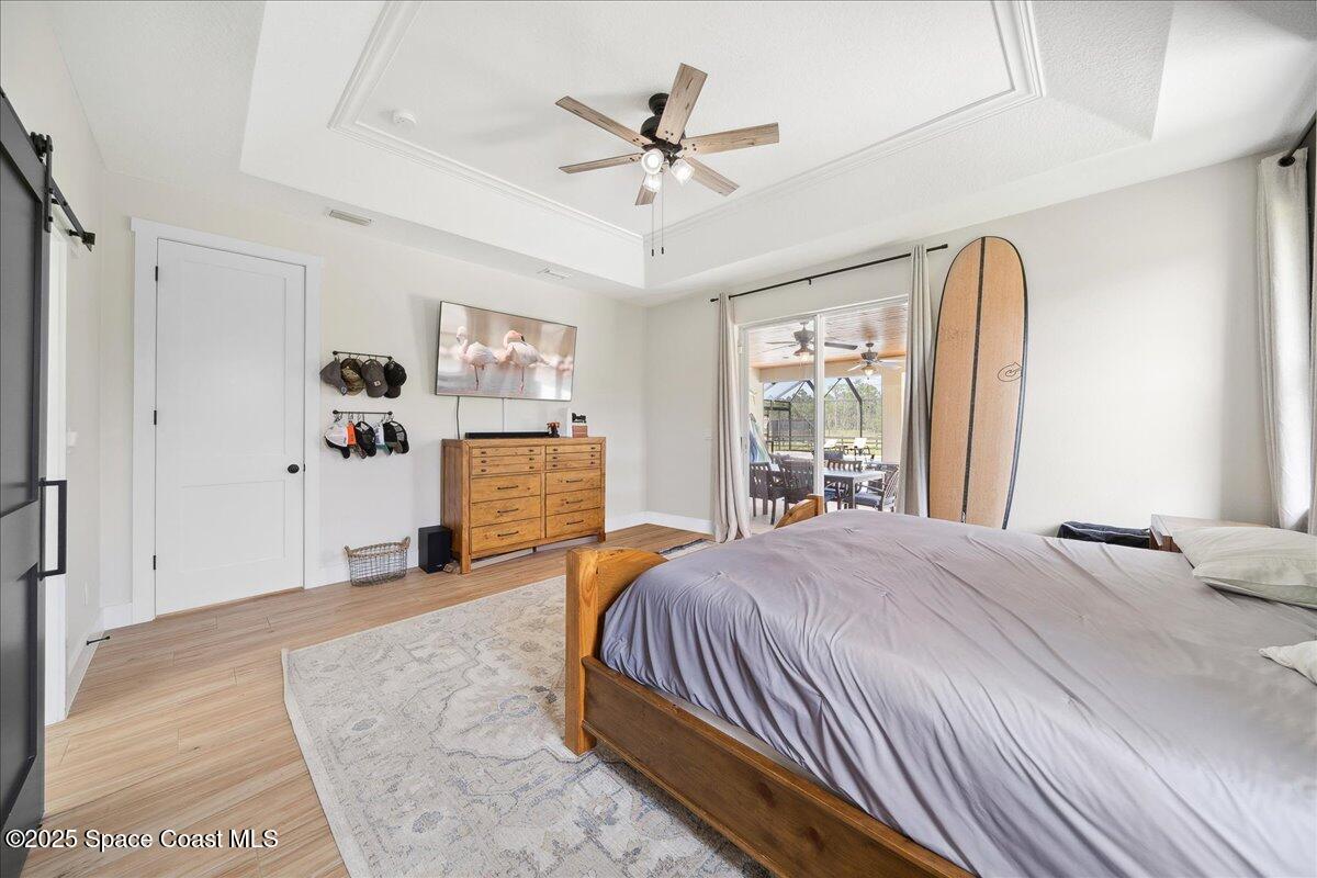 5005 Corey Road Grant Valkaria, FL 32950 - Photo 19 of 47 a bedroom with a large bed and a chandelier