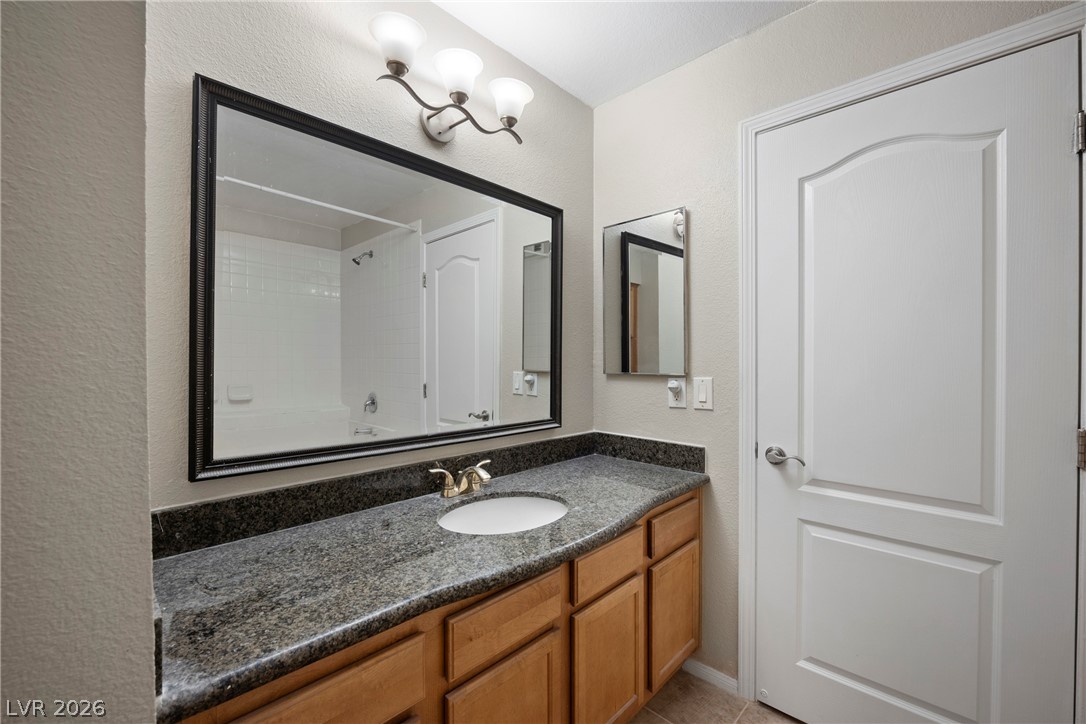 3145 East Flamingo Road, Unit 1055 Las Vegas, NV 89121 - Photo 30 of 40 Elegant granite countertops and warm wood cabinetry define this well-appointed bathroom vanity area.