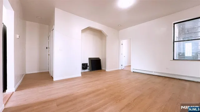 a view of an empty room with window and wooden floor